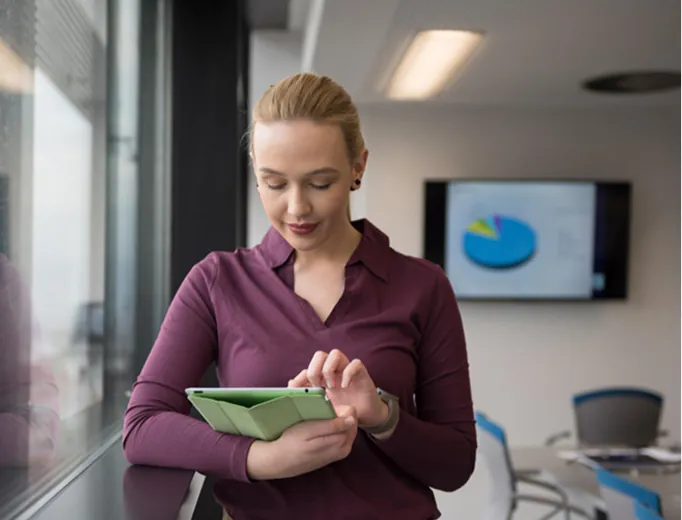 Professional reviewing results on a tablet by a window
