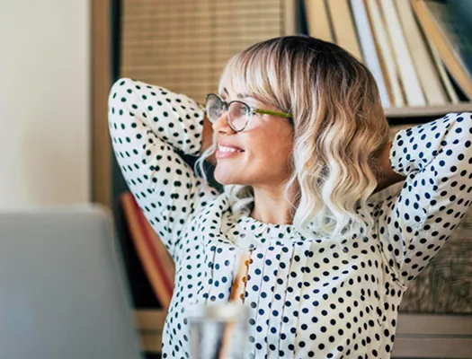 Relaxed employee leaning back at her desk, smiling
