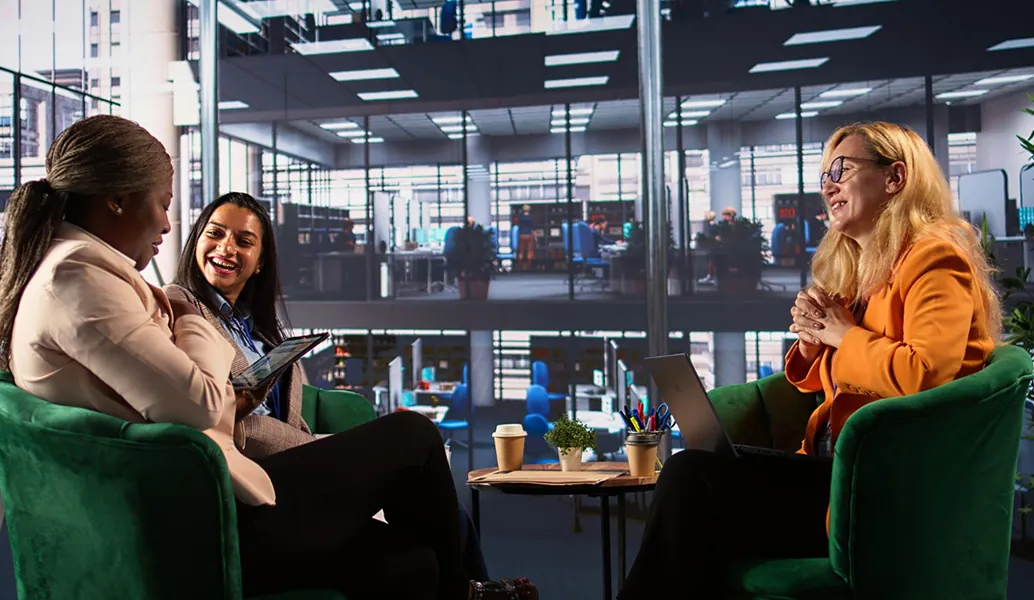 Colleagues chatting on green armchairs in a modern office lounge