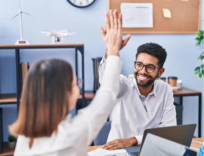 Two colleagues high-fiving during a kick-off meeting