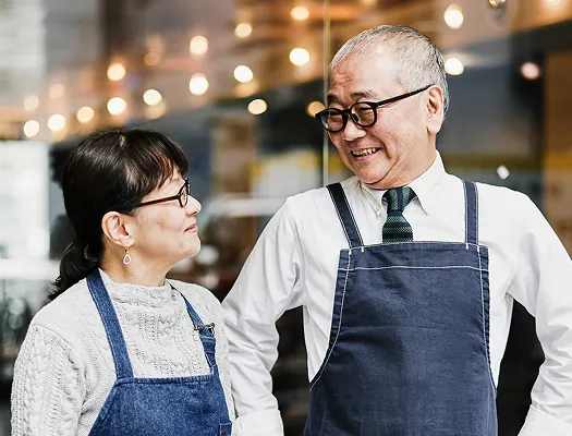 Two colleagues in aprons talking cheerfully at work